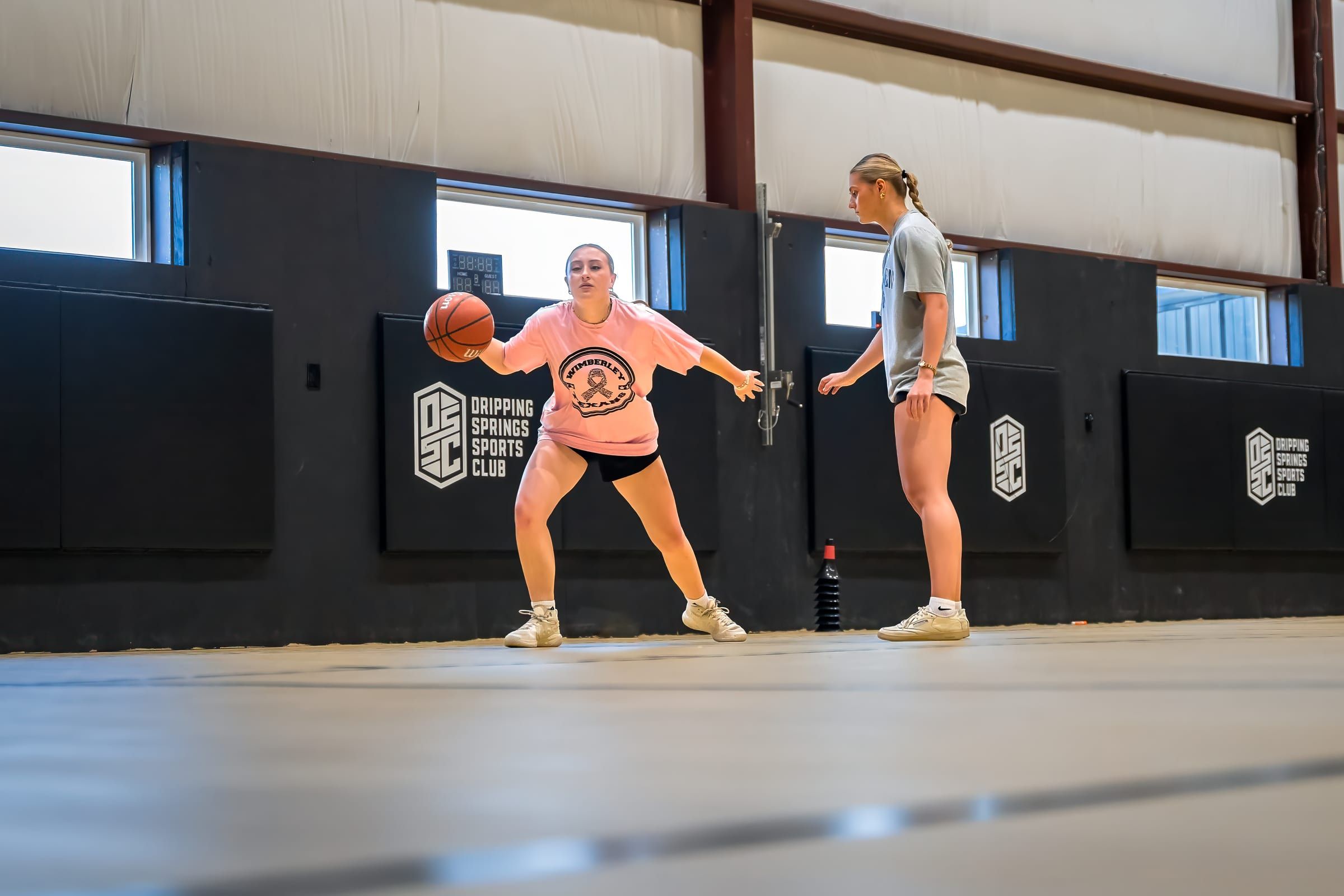 Two players in a dribbling drill as a coach watches