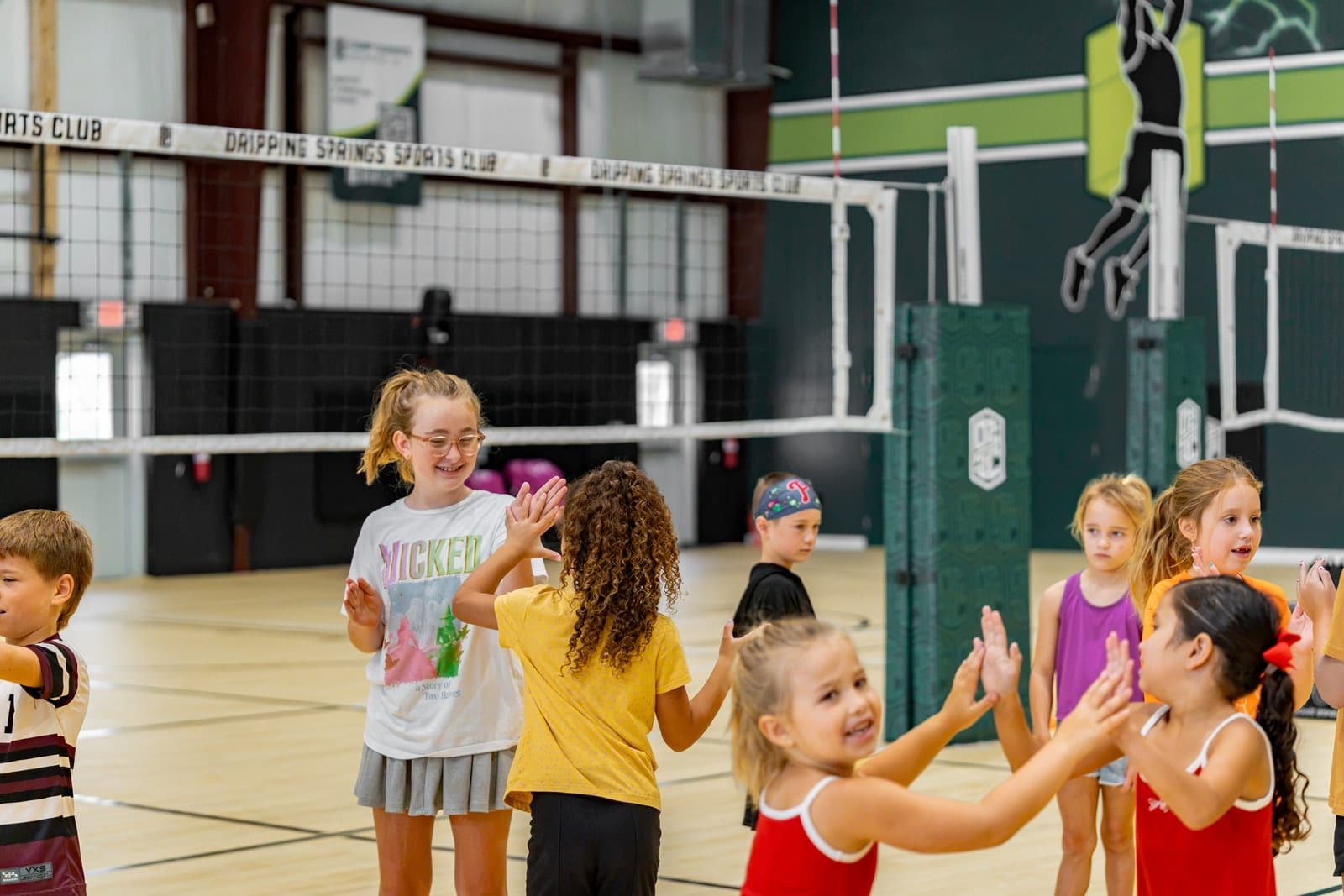 Young campers high-fiving a coach on the court