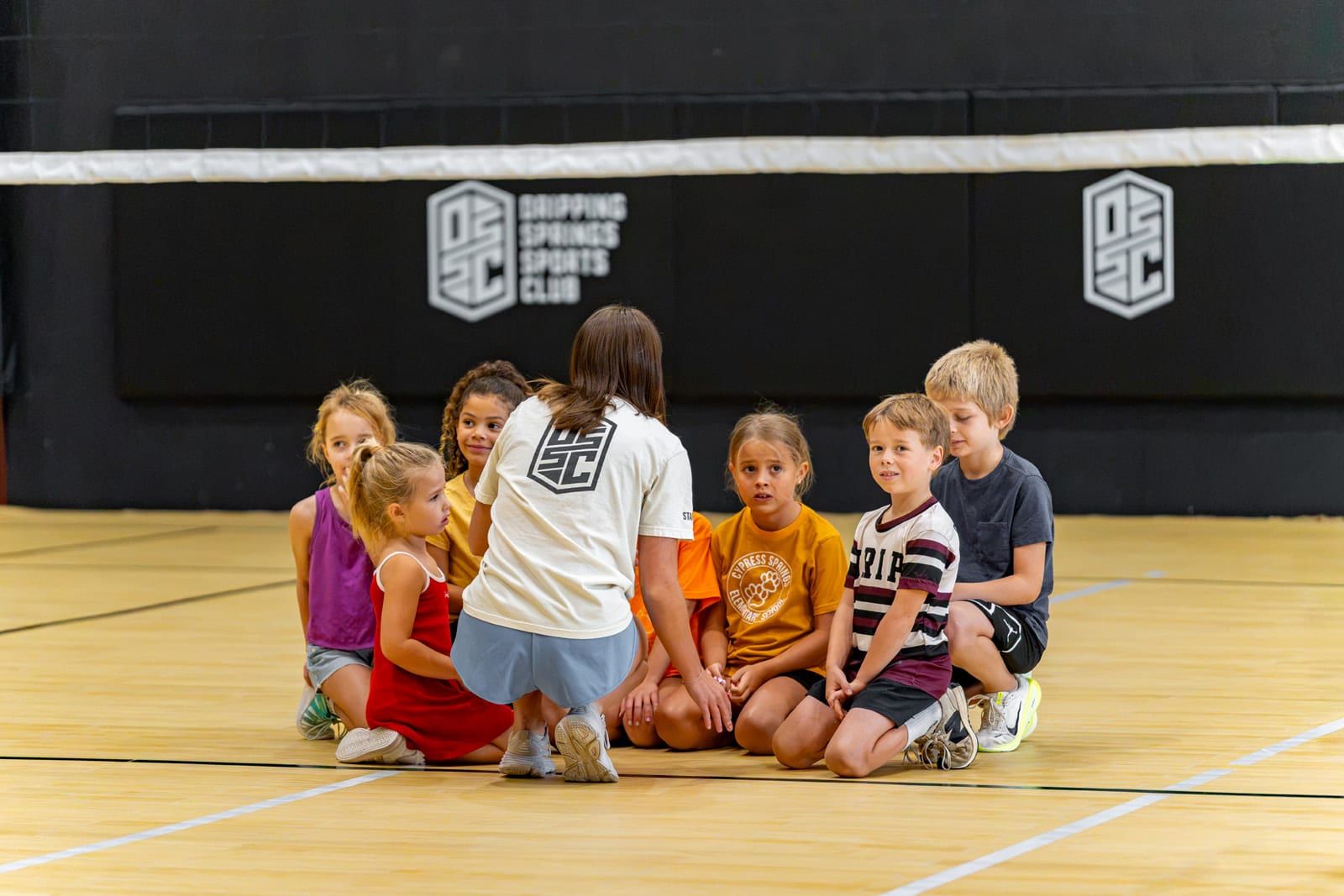 Campers sitting with a coach on the court