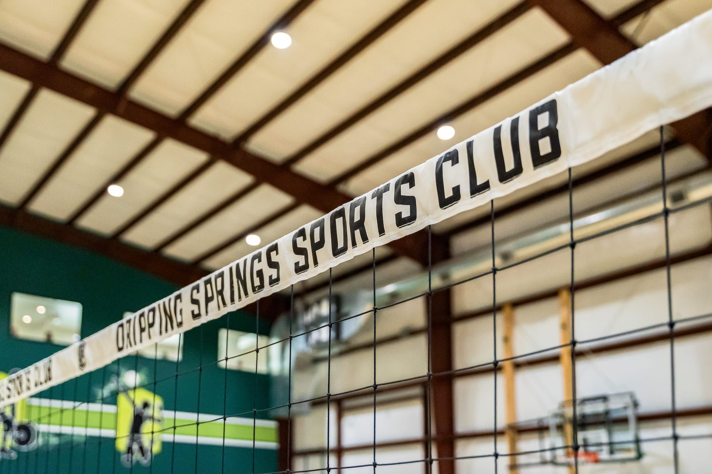 The Dripping Springs Sports Club banner along the top of a volleyball net
